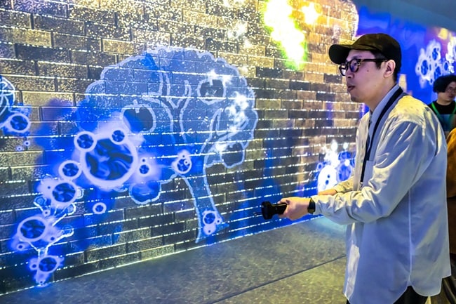 A person pointing a controller at a wall with visuals projected on it