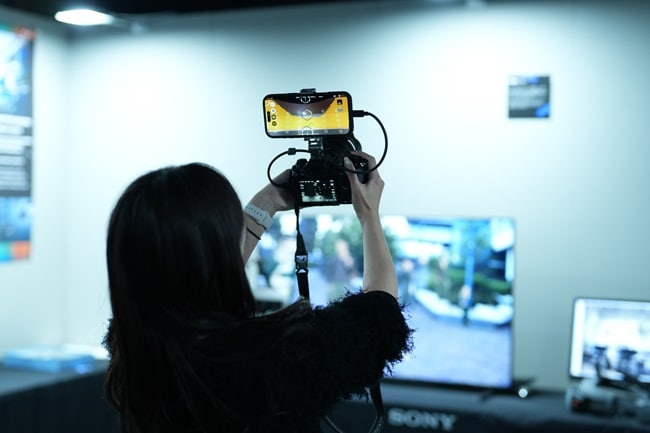 A person taking photos with a camera connected to a smartphone