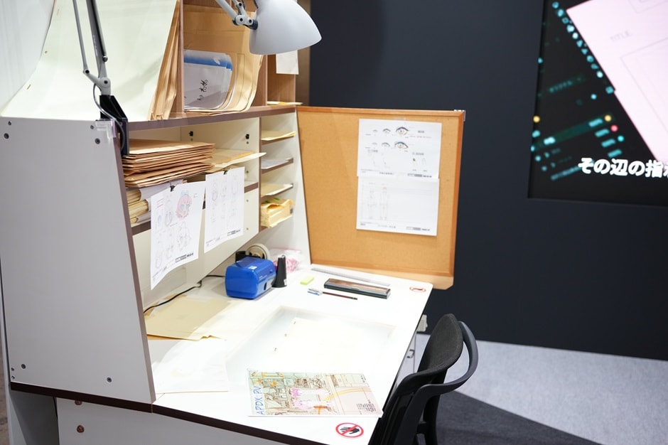 A display modeled after a creator’s desk, with reference materials posted on the shelf and numerous paper envelopes stored neatly.