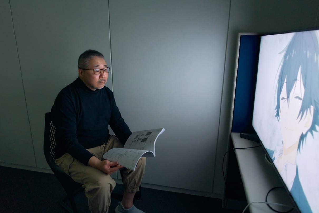 Director Ishihama checking video material on a large screen.