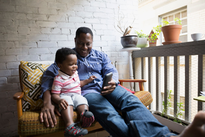 Grandfather and grandchild looking at phone while sitting on a bench