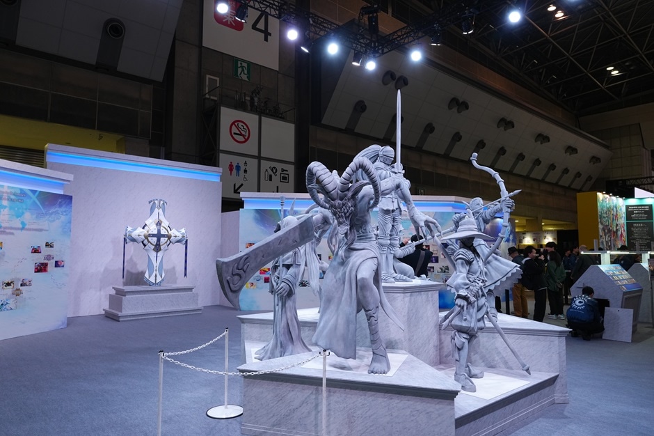 パネルが曲線状に並び、中央にグレーで統一された複数のキャラクターのオブジェが展示されている様子